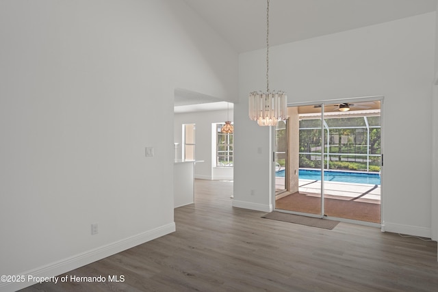 8410 Lakehill Ct, Spring Hill, FL 34608 - unfurnished dining area with high vaulted ceiling, wood finished floors, ceiling fan, and a chandelier