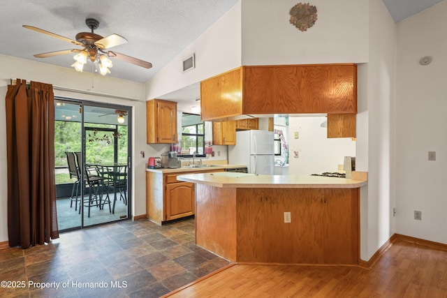 13345 Convent Garden Rd, Brooksville, FL 34613 - kitchen with freestanding refrigerator, ceiling fan, light countertops, vaulted ceiling, and a peninsula