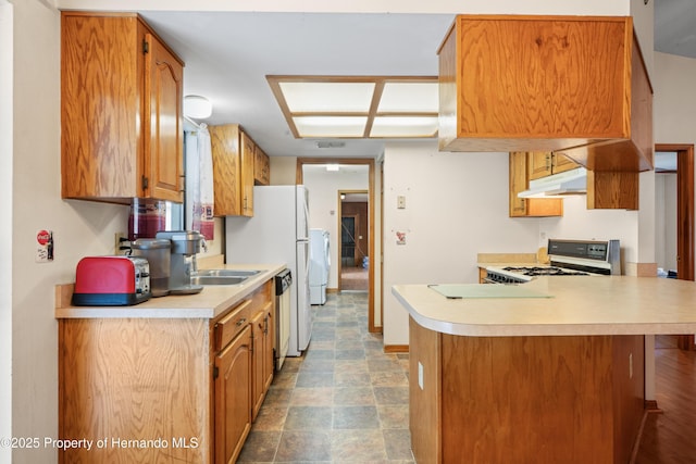 13345 Convent Garden Rd, Brooksville, FL 34613 - kitchen featuring range with gas cooktop, light countertops, under cabinet range hood, a peninsula, and brown cabinets
