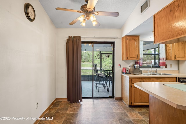13345 Convent Garden Rd, Brooksville, FL 34613 - kitchen with light countertops, a ceiling fan, stone finish flooring, and brown cabinets