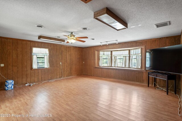13345 Convent Garden Rd, Brooksville, FL 34613 - unfurnished living room with light wood-style floors, wooden walls, a textured ceiling, and a ceiling fan