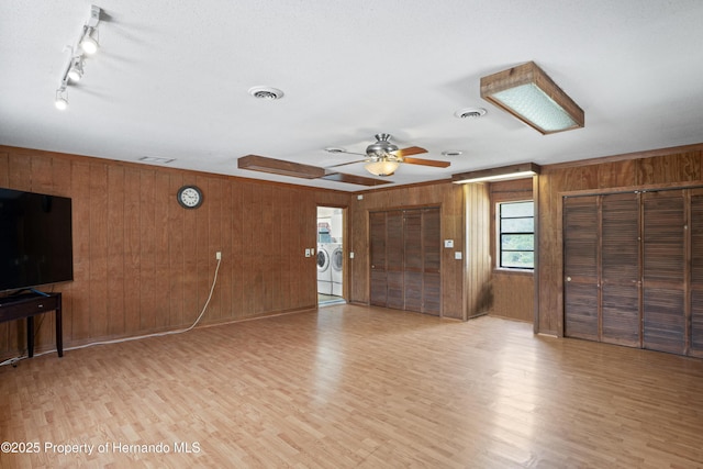13345 Convent Garden Rd, Brooksville, FL 34613 - unfurnished living room featuring wood walls, washer and dryer, light wood-style flooring, and a ceiling fan
