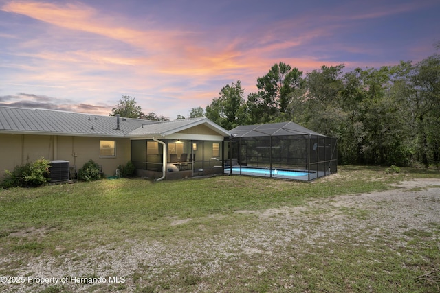 13345 Convent Garden Rd, Brooksville, FL 34613 - back of property at dusk with a detached carport, a metal roof, a lawn, and a lanai