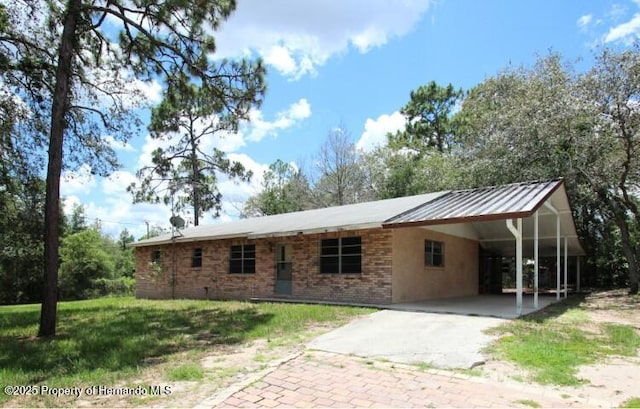 6275 Casson St, Brooksville, FL 34604 - ranch-style home featuring driveway, an attached carport, brick siding, a front lawn, and a metal roof