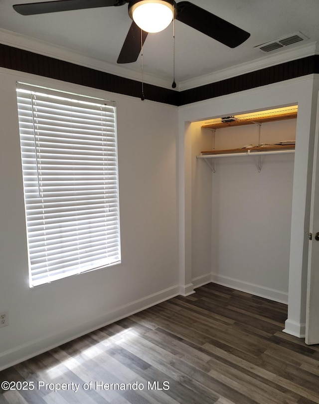 18499 Shady Side Dr, Brooksville, FL 34601 - unfurnished bedroom with wood finished floors, crown molding, a closet, a ceiling fan, and multiple windows