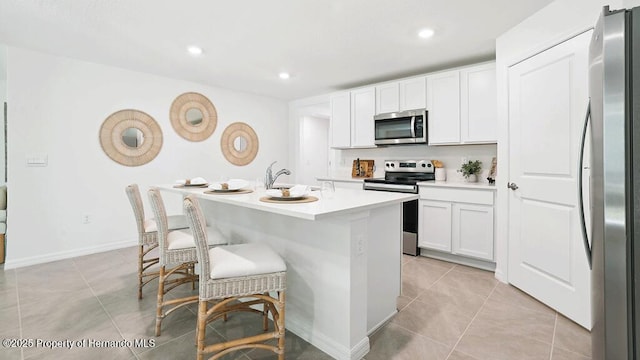 7163 N Folgers Ter, Dunnellon, FL 34433 - kitchen featuring appliances with stainless steel finishes, light tile patterned floors, a center island with sink, light countertops, and white cabinets