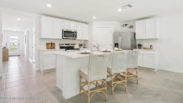 7163 N Folgers Ter, Dunnellon, FL 34433 - kitchen featuring appliances with stainless steel finishes, light tile patterned floors, a kitchen island with sink, light countertops, and white cabinetry