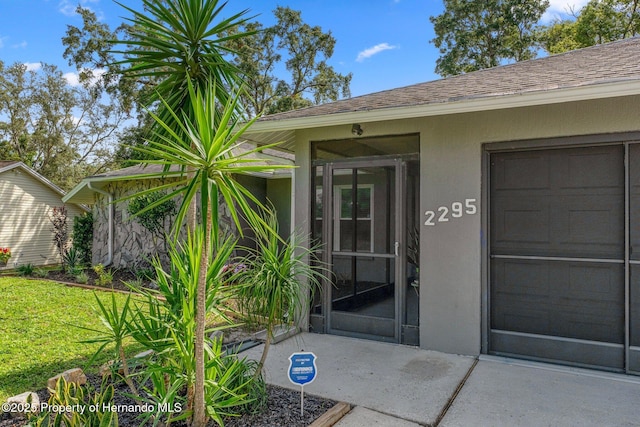 2295 Rio Cir, Spring Hill, FL 34608 - view of exterior entry with stucco siding, a yard, and a shingled roof