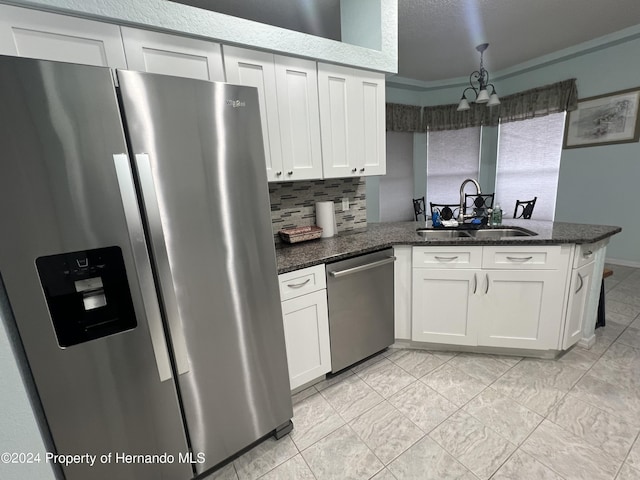 5388 Idleweise Ct, Spring Hill, FL 34606 - kitchen with appliances with stainless steel finishes, a peninsula, white cabinets, dark stone counters, and a chandelier