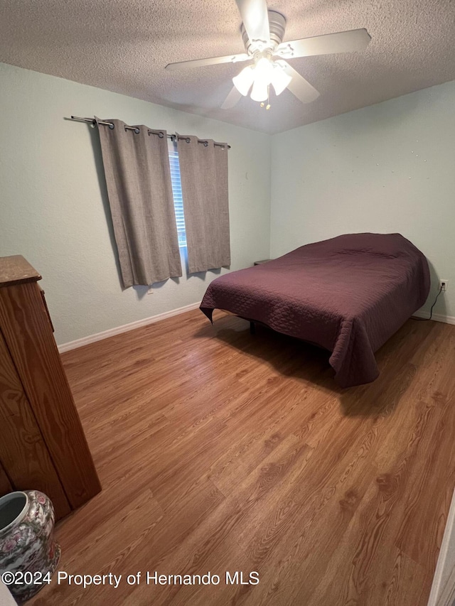 5388 Idleweise Ct, Spring Hill, FL 34606 - bedroom with wood finished floors, a textured ceiling, and ceiling fan