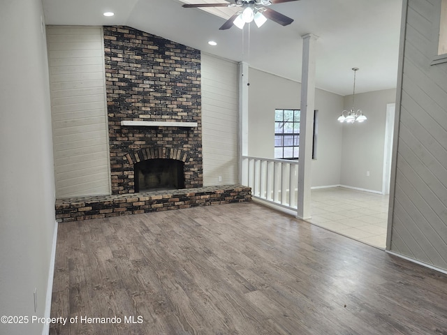 18232 Monteverde Dr, Spring Hill Pasco, FL 34610 - unfurnished living room featuring lofted ceiling, wood finished floors, ceiling fan, a brick fireplace, and wooden walls