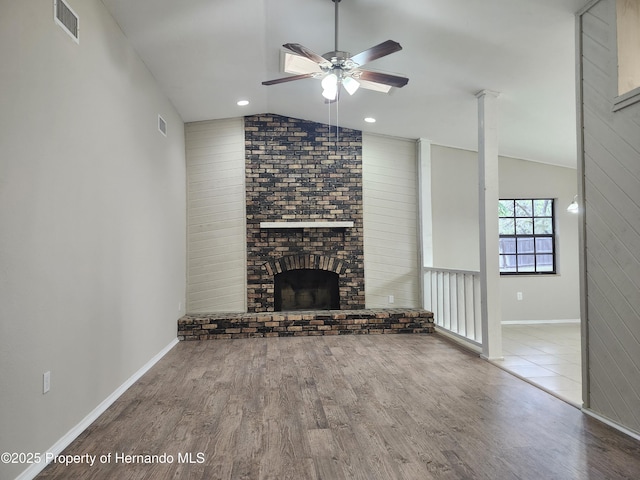 18232 Monteverde Dr, Spring Hill Pasco, FL 34610 - unfurnished living room featuring vaulted ceiling, wood finished floors, a ceiling fan, and a fireplace