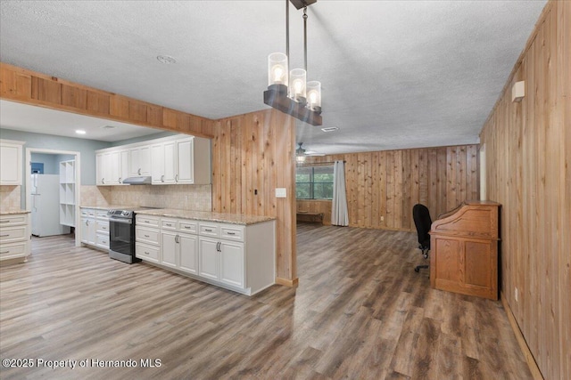 1518 Palm St, Steinhatchee, FL 32359 - kitchen with stainless steel electric stove, freestanding refrigerator, light wood-type flooring, decorative backsplash, and white cabinets