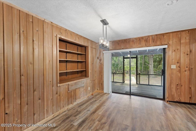 1518 Palm St, Steinhatchee, FL 32359 - unfurnished dining area with wooden walls, a textured ceiling, built in shelves, and wood finished floors