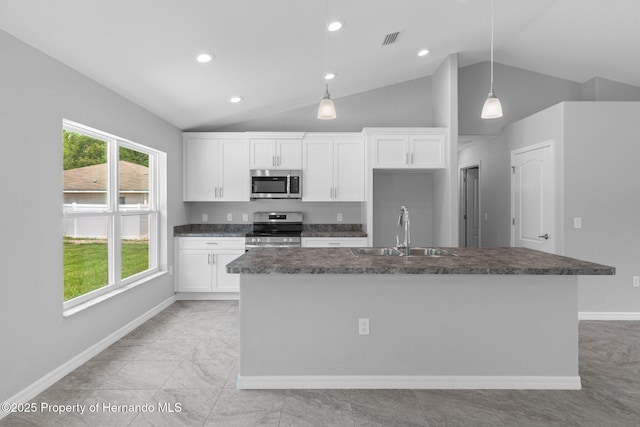 12128 Petrel Ave, Brooksville, FL 34614 - kitchen featuring appliances with stainless steel finishes, dark countertops, lofted ceiling, white cabinets, and a center island with sink