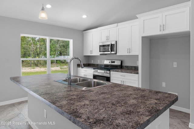 12128 Petrel Ave, Brooksville, FL 34614 - kitchen featuring appliances with stainless steel finishes, dark countertops, white cabinetry, a kitchen island with sink, and vaulted ceiling