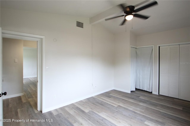 9345 N Elliot Way, Citrus Springs, FL 34434 - unfurnished bedroom with multiple closets, wood finished floors, and a ceiling fan