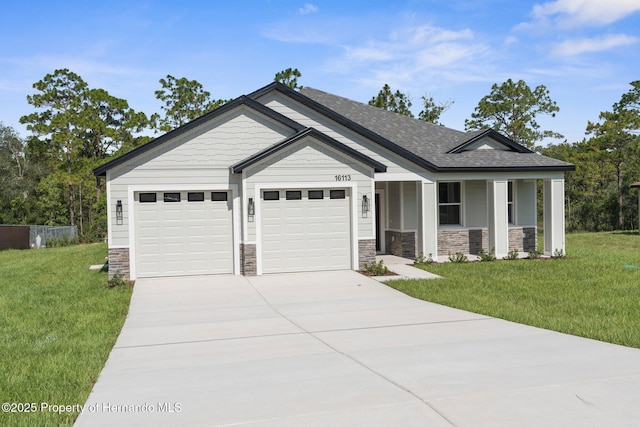 16113 Penn State Rd, Weeki Wachee, FL 34614 - view of front facade featuring an attached garage, concrete driveway, a front yard, stone siding, and covered porch