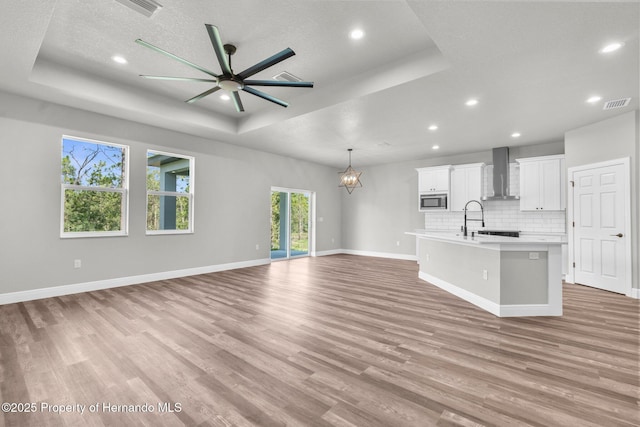 16113 Penn State Rd, Weeki Wachee, FL 34614 - unfurnished living room featuring a raised ceiling, ceiling fan, light wood-style floors, a chandelier, and recessed lighting