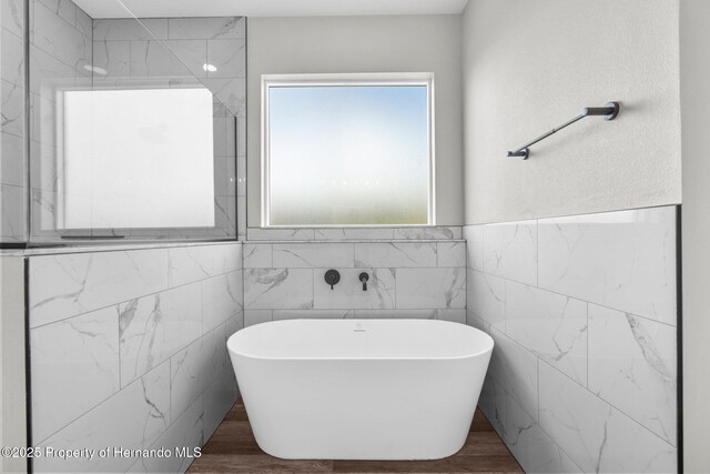 16113 Penn State Rd, Weeki Wachee, FL 34614 - bathroom featuring a freestanding bath, tile walls, and wood finished floors
