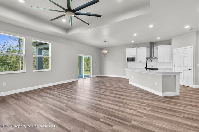 16113 Penn State Rd, Weeki Wachee, FL 34614 - unfurnished living room featuring a raised ceiling, recessed lighting, wood finished floors, a chandelier, and ceiling fan