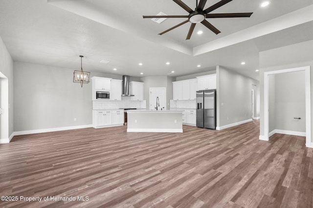16113 Penn State Rd, Weeki Wachee, FL 34614 - unfurnished living room featuring a ceiling fan, recessed lighting, wood finished floors, a chandelier, and a tray ceiling