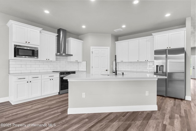 16113 Penn State Rd, Weeki Wachee, FL 34614 - kitchen with stainless steel appliances, wall chimney range hood, decorative backsplash, white cabinetry, and a kitchen island with sink