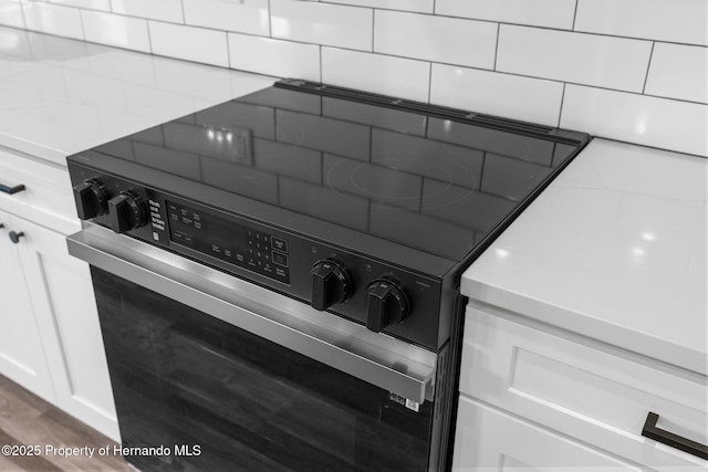 16113 Penn State Rd, Weeki Wachee, FL 34614 - kitchen view of black electric range oven, white cabinetry, and dark wood-style floors
