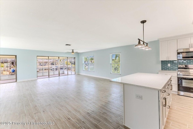 4016 Centavo Ct, Hernando Beach, FL 34607 - kitchen with appliances with stainless steel finishes, light countertops, a ceiling fan, tasteful backsplash, and light wood-style floors
