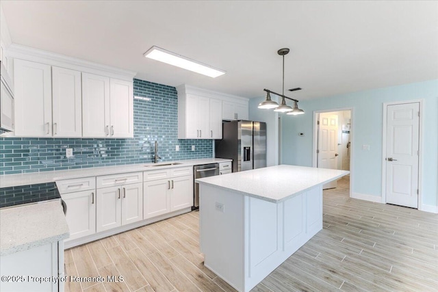 4016 Centavo Ct, Hernando Beach, FL 34607 - kitchen featuring appliances with stainless steel finishes, light wood-type flooring, tasteful backsplash, white cabinets, and a kitchen island