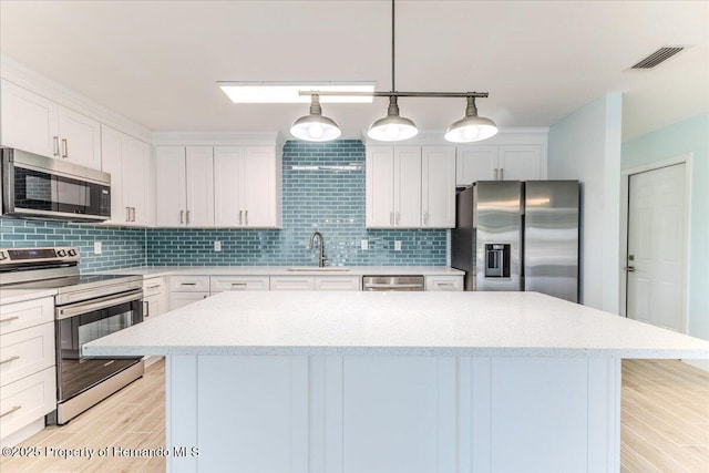 4016 Centavo Ct, Hernando Beach, FL 34607 - kitchen featuring appliances with stainless steel finishes, a center island, backsplash, and white cabinets