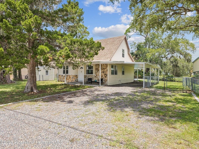 3579 Eagle Nest Dr, Hernando Beach, FL 34607 - rear view of house featuring an attached carport, driveway, stone siding, roof with shingles, and a gate