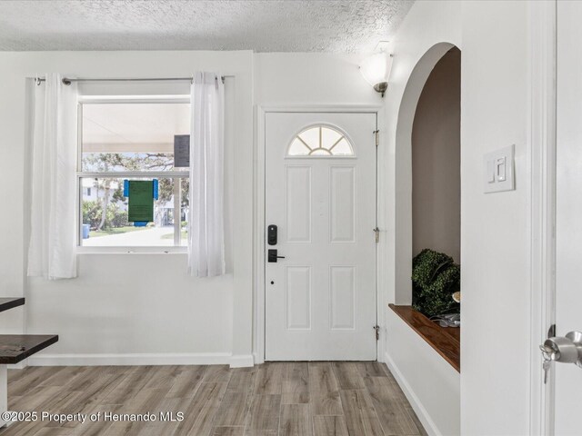 3579 Eagle Nest Dr, Hernando Beach, FL 34607 - entryway with arched walkways, wood finished floors, a textured ceiling, and healthy amount of natural light