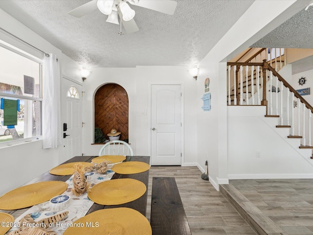 3579 Eagle Nest Dr, Hernando Beach, FL 34607 - dining area with wood finished floors, ceiling fan, stairway, a textured ceiling, and arched walkways