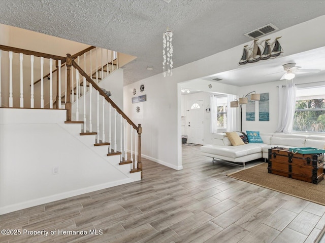 3579 Eagle Nest Dr, Hernando Beach, FL 34607 - living room with wood finished floors, stairs, a ceiling fan, and a textured ceiling