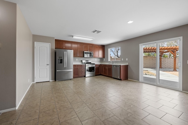 kitchen with a sink, light countertops, stainless steel appliances, baseboards, and visible vents
