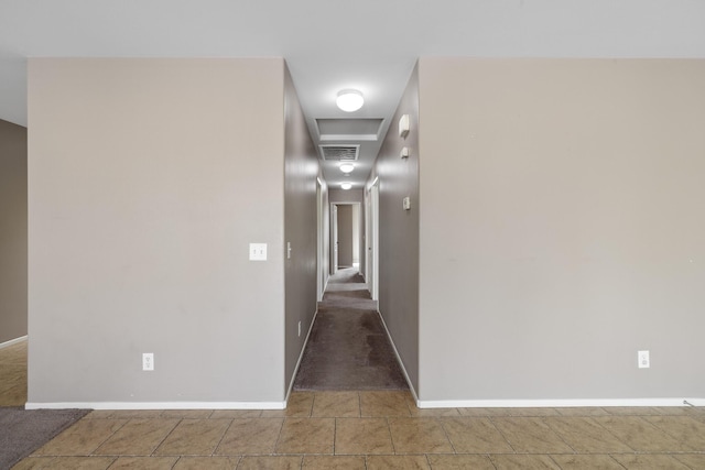 hall with visible vents, baseboards, and tile patterned floors