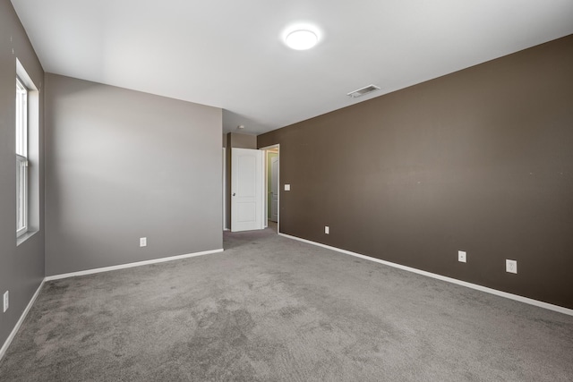 carpeted spare room featuring baseboards and visible vents