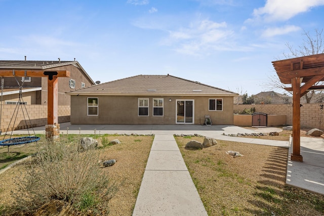 back of property with a fenced backyard, a patio area, stucco siding, and a storage shed
