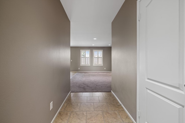 hallway with light colored carpet, recessed lighting, baseboards, and light tile patterned floors
