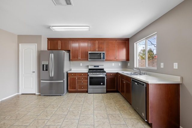 kitchen with a sink, appliances with stainless steel finishes, light countertops, and visible vents