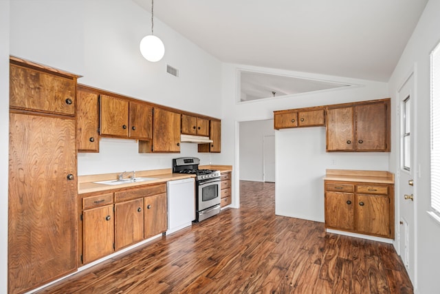 kitchen with light countertops, brown cabinets, stainless steel gas stove, and a sink