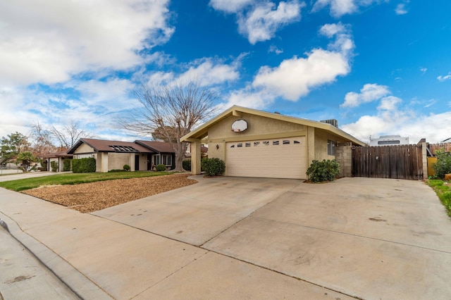 view of front facade with stucco siding, concrete driveway, a garage, and fence