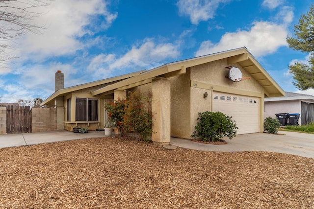 view of front of property with fence, concrete driveway, stucco siding, a chimney, and an attached garage