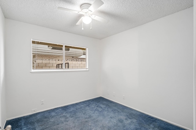 empty room with baseboards, a ceiling fan, dark carpet, and a textured ceiling