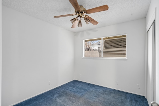 unfurnished room featuring baseboards, a textured ceiling, ceiling fan, and dark colored carpet