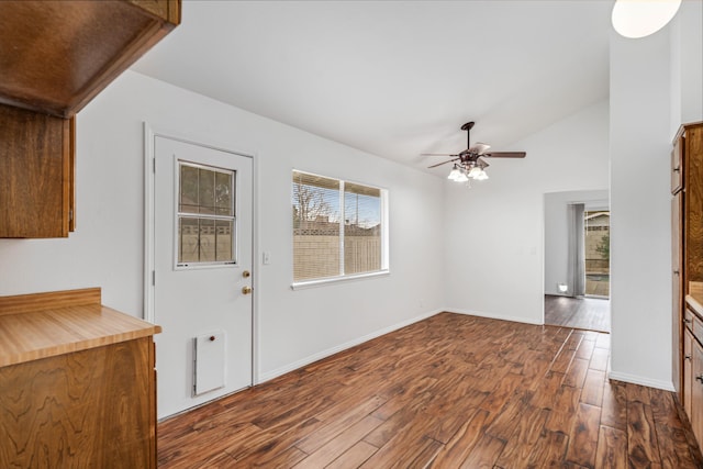 unfurnished dining area with baseboards, lofted ceiling, dark wood-style floors, and a ceiling fan