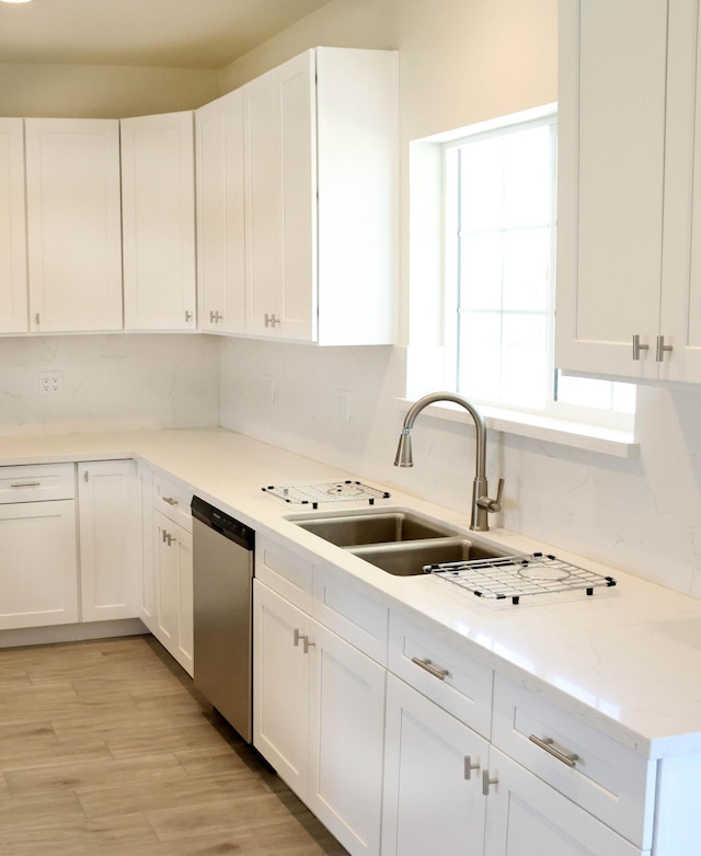 kitchen with stainless steel dishwasher, white cabinetry, and a sink