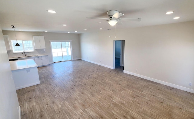 unfurnished living room with a sink, baseboards, light wood-style floors, ceiling fan, and recessed lighting