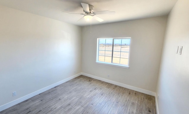 empty room with a ceiling fan, light wood-style flooring, and baseboards